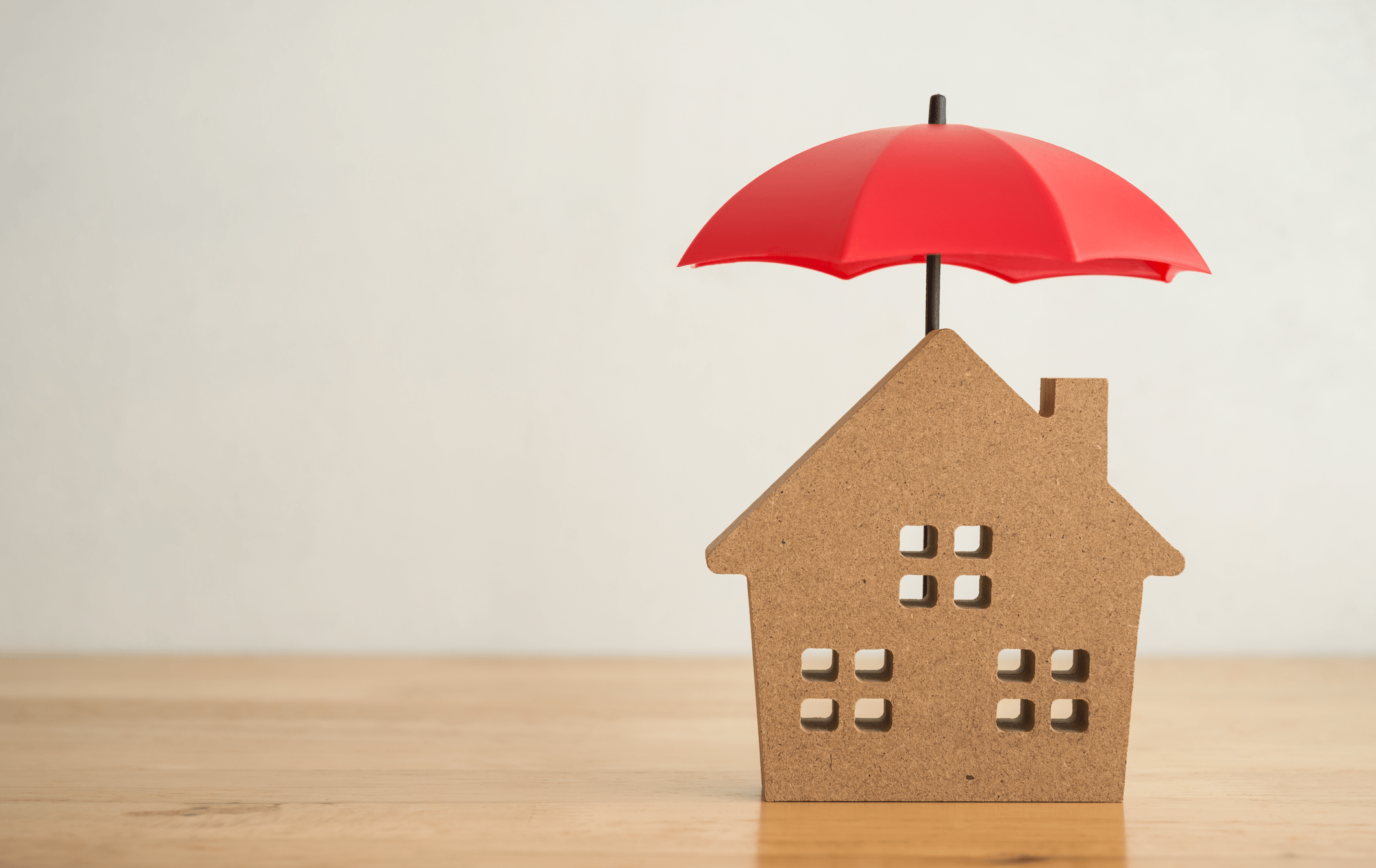Red umbrella cover home model on office wooden table with white wall background