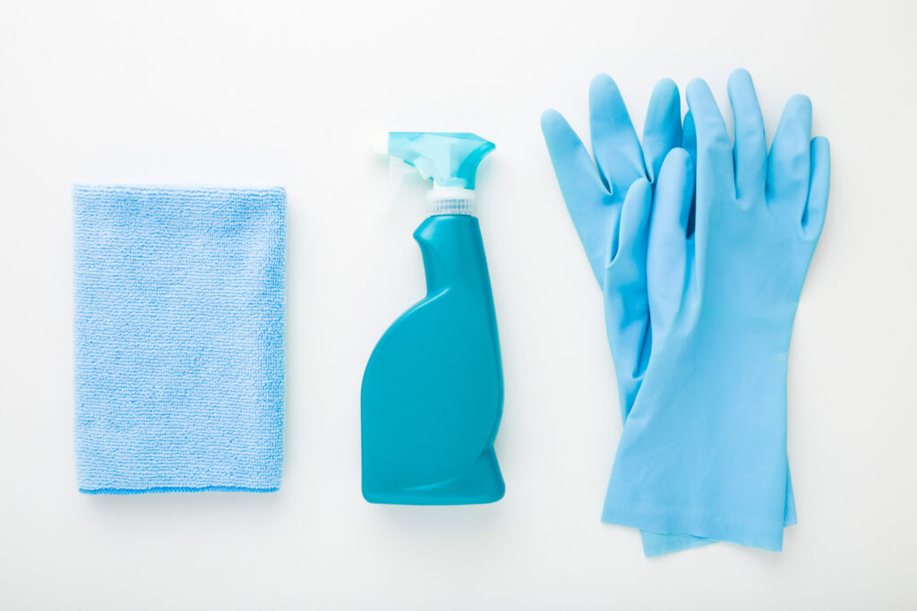 A blue cleaning cloth, spray and gloves.